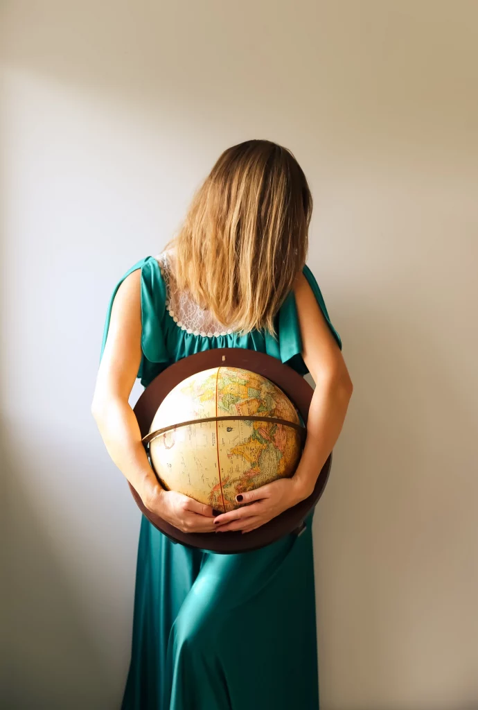 woman in teal dress holding globe