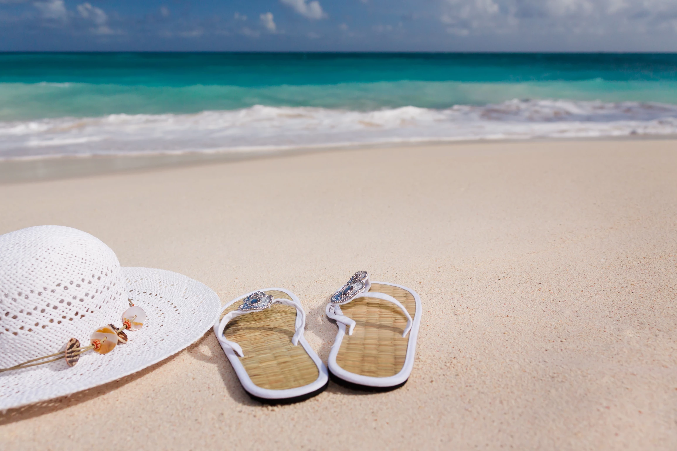 hat and flipflop beside the beach